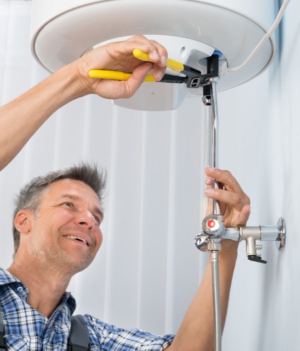 Portrait Of Happy Male Plumber Repairing Electric Boiler